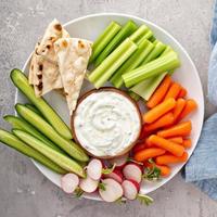 Large snack board with tzatziki dip or sauce and fresh vegetables photo