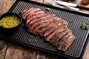 Grilled flank steak with chimichurri sauce on a grill pan photo