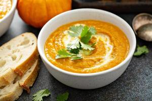 Pumpkin soup served with cream and cilantro photo