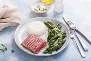 Seared tuna steak with white rice and green peas photo