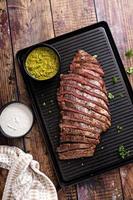 Grilled flank steak with chimichurri sauce on a grill pan photo