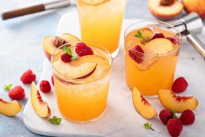 Refreshing summer cocktail with peach and raspberry photo