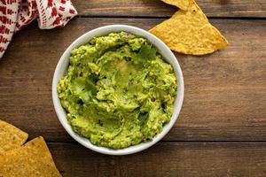 grueso guacamole casero en un tazón con chips de tortilla foto