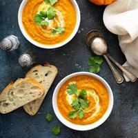 Pumpkin soup served with cream and cilantro photo