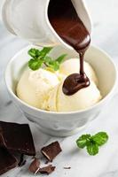 Pouring chocolate sauce on ice cream photo