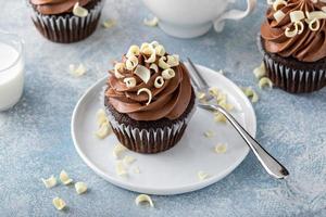 Dark chocolate cupcakes with whipped ganache frosting and white chocolate curls photo