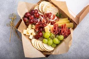 tabla de embutidos en una caja con queso y carne foto