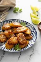 Fried caramelized plantains served with lime wedges photo