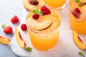 Refreshing summer cocktail with peach and raspberry photo