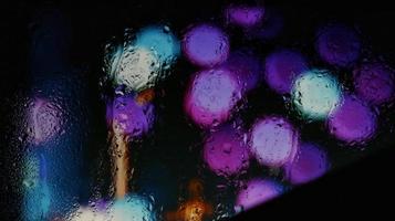 Purple Neon Blurred Lights Through Glass Window With Raindrops On It in Karachi Pakistan 2022 photo