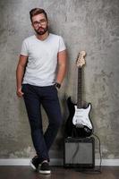 Stylish bearded guy with guitar against concrete wall photo