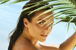 Beautiful woman with a palm leaf on the beach photo