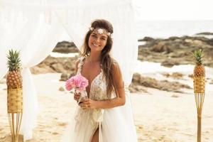 Happy smiling bride in beautiful wedding dress on the beach photo