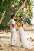 pareja joven y hermosa está celebrando la boda en la playa foto