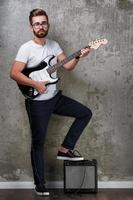 Stylish bearded guy with guitar against concrete wall photo