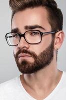 hombre barbudo elegante en anteojos contra fondo gris foto