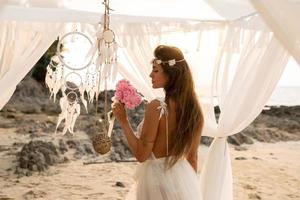 hermosa joven novia celebrando la boda en la playa foto