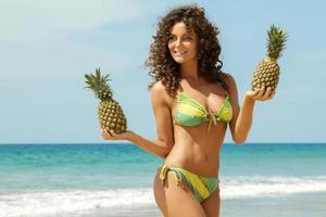 mujer con piña en la playa foto