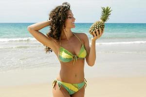 mujer con una fruta de piña en la playa foto