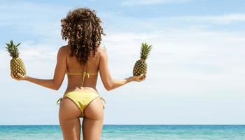 Woman with a pineapple fruit on the beach photo