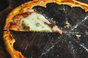 Last piece of delicious pizza on the wooden board photo