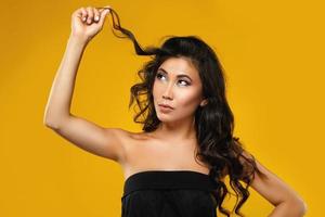 Asian woman with a beautiful curly hair and make-up on yellow background photo