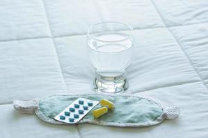 Blister pack of sleeping pills, blindfold and glass of water photo