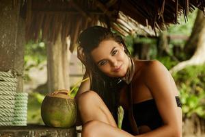 una mujer feliz disfruta de una bebida de coco en el bar de la playa foto