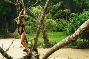 Sexy woman with coconut cocktail posing beside old tree photo
