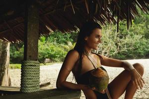 Happy woman is enjoying coconut drink in the beach bar photo