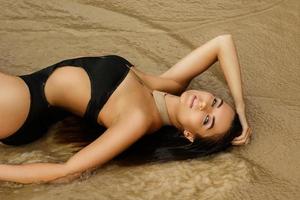 Woman is lying in wet sand on the beach photo