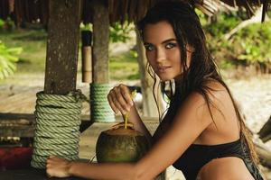 Happy woman is enjoying coconut drink in the beach bar photo