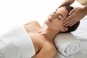 Young and beautiful woman during facial massage session photo