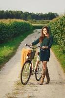 Woman is cycling by the country road in the cornfield photo