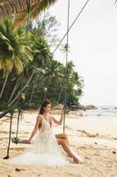 hermosa novia con vestido de novia en la playa tropical foto