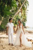 pareja joven y hermosa está celebrando la boda en la playa foto