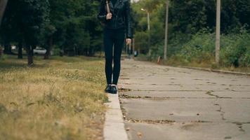 girl in black jeans and leather jacket walks on a border in the street video