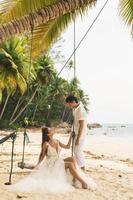 feliz joven pareja casada celebrando su boda en la playa foto