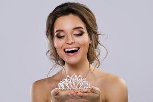 Portrait of young beautiful bride holding diadem photo