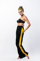 Stylish woman with yellow hair and trackpants on gray background
