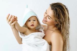 Young and happy mother and her cute little baby after bathing photo