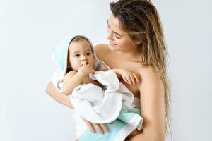 Young and happy mother and her cute little baby after bathing photo