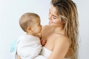 Young and happy mother and her cute little baby after bathing photo