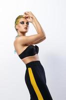 Stylish woman with yellow hair and trackpants on gray background photo