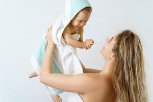 Young and happy mother and her cute little baby after bathing photo