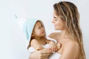 Young and happy mother and her cute little baby after bathing photo