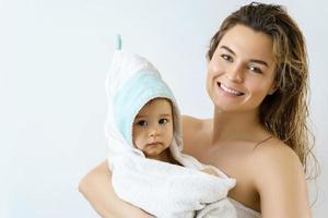 Young and happy mother and her cute little baby after bathing photo