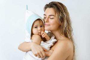 Young and happy mother and her cute little baby after bathing photo