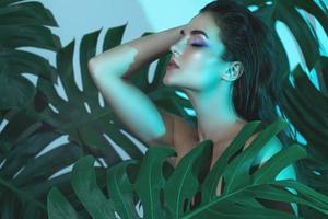 Young and beautiful woman with perfect smooth skin in tropical leaves photo