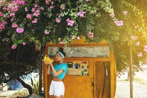 Happy woman with a bunch of bananas posing beside old filling station photo